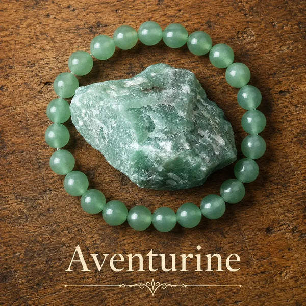 Pulsera elástica de cuentas redondas de aventurina verde clara y traslúcida, junto a un trozo en bruto de la misma piedra sobre madera