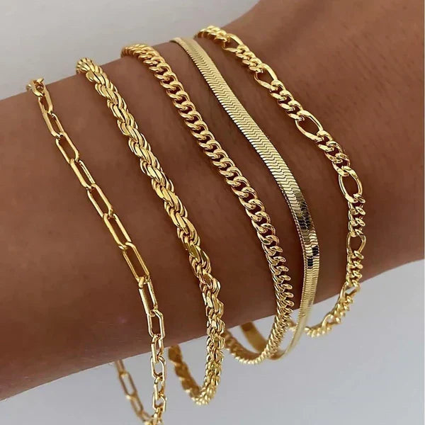 Cinco pulseras de cadena en tono dorado combinadas en la muñeca