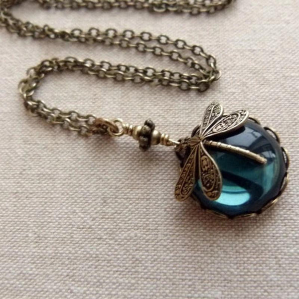 Collar de cadena en tono bronce envejecido con un cristal redondo azul verdoso montado en un cerco labrado y una libélula posada encima