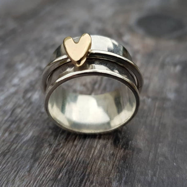 Anillo de banda con un corazón dorado sobre acabado plateado