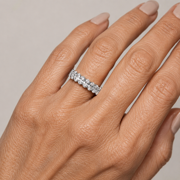 Anillo plateado con circonitas engastadas alrededor de toda la banda, puesto en un dedo