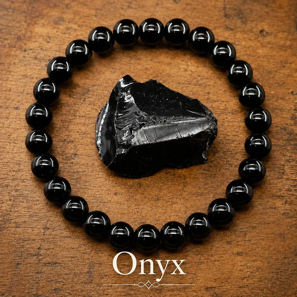 Pulsera elástica de cuentas redondas de ónice negro pulido, junto a un fragmento en bruto de la misma piedra sobre madera