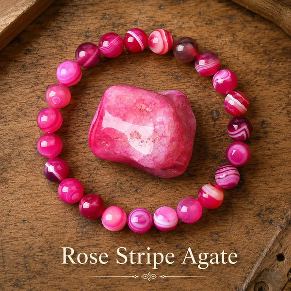 Pulsera elástica de cuentas redondas de ágata rosa fuerte con bandas blancas curvadas, junto a un trozo pulido de la misma piedra