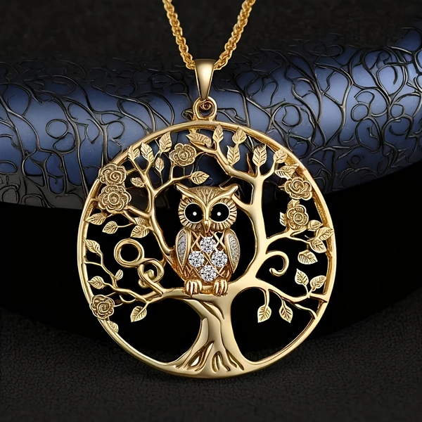 Collar en acabado dorado con un colgante redondo calado que forma un árbol con raíces, flores y un búho posado en una rama con cristales en el pecho