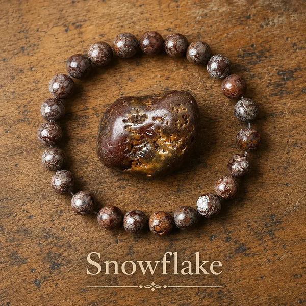 Pulsera elástica de cuentas redondas de piedra marrón caoba con motas grises y blancas, junto a un canto rodado de la misma piedra