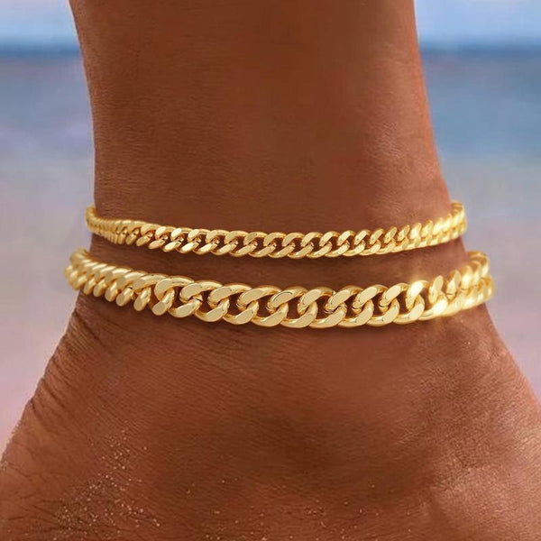 Tobillera de dos vueltas de cadena cubana en acabado dorado, puesta sobre el tobillo, con los eslabones planos y bien apretados