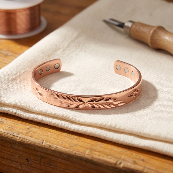 Pulsera rígida de cobre con aberturas caladas en forma de hoja repartidas a lo largo de la banda y tres imanes en cada extremo