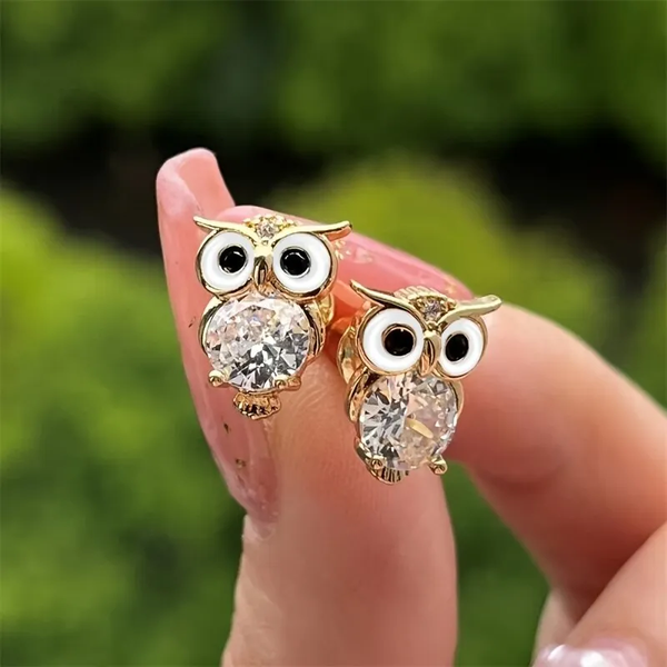Pendientes de botón con forma de búho en acabado dorado, ojos redondos blancos y negros y un cristal facetado grande como cuerpo