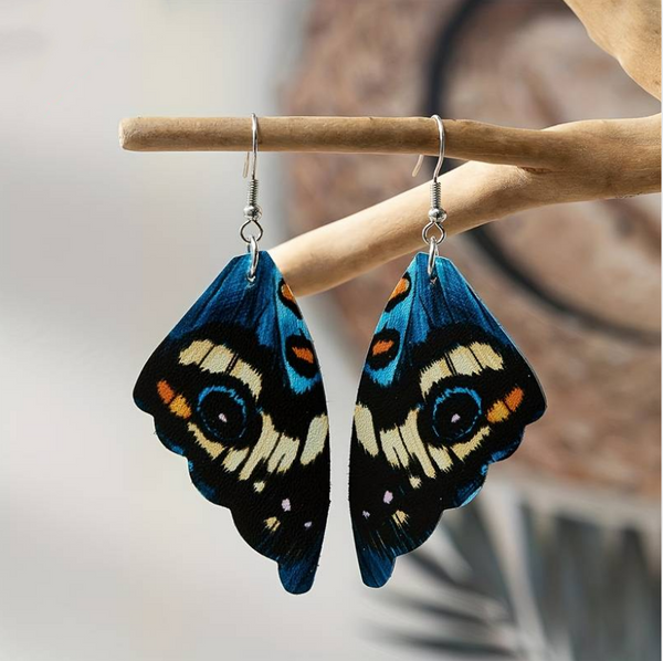 Pendientes colgantes con forma de ala de mariposa en negro con franjas color crema, puntos azules y toques naranjas, en gancho plateado