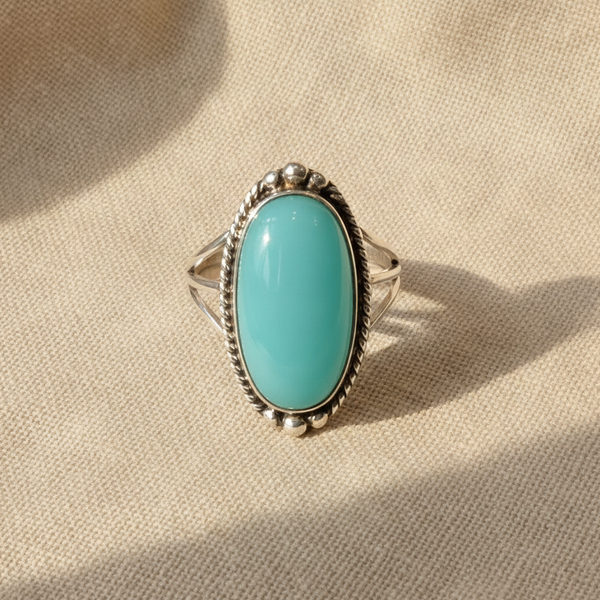 Anillo con piedra turquesa ovalada grande sobre montura trenzada