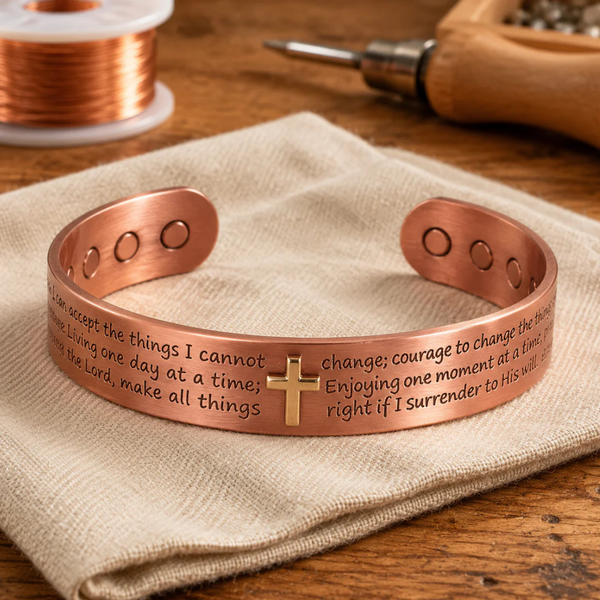 Pulsera rígida de cobre con una cruz en relieve en el centro y un texto grabado alrededor, con tres imanes redondos en cada extremo
